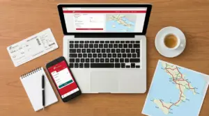 Laptop con sito Trenitalia, smartphone, biglietto del treno e mappa del Sud Italia su un tavolo