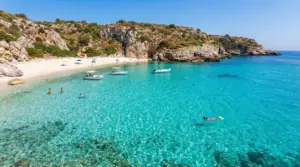 Spiaggia del Sud Italia con acqua cristallina, bagnanti e barche vicino alla riva